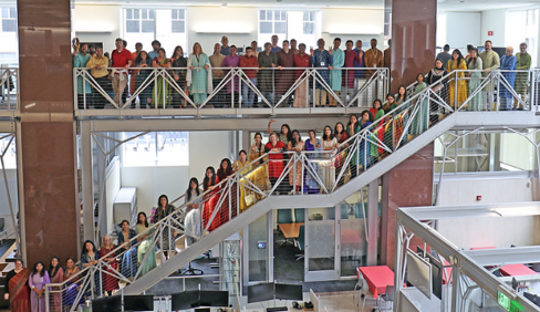 Large group of people posing on a staircase and balcony inside a multi-level office building.