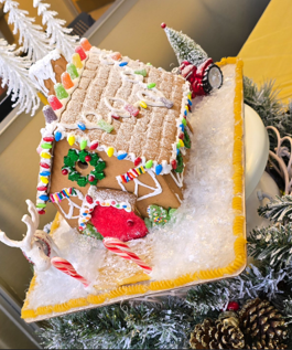 Decorated gingerbread house on a holiday-themed display with snow and candy details.
