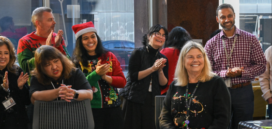 Group of colleagues clapping and smiling at a holiday event.