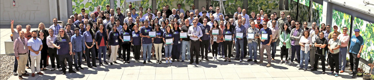 Large group of employees posing outdoors, some holding awards.