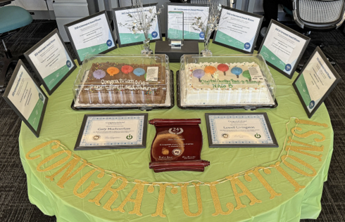 Table display with cakes, certificates, and a ‘Congratulations’ banner for an awards celebration.